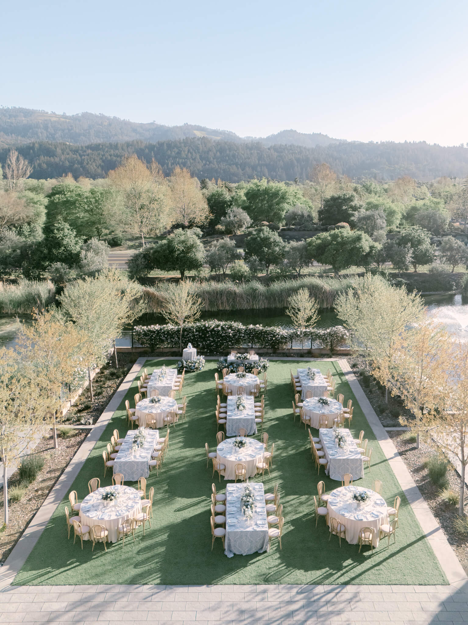 Drone image of a reception space with round and rectangle tables and mountains in the background.