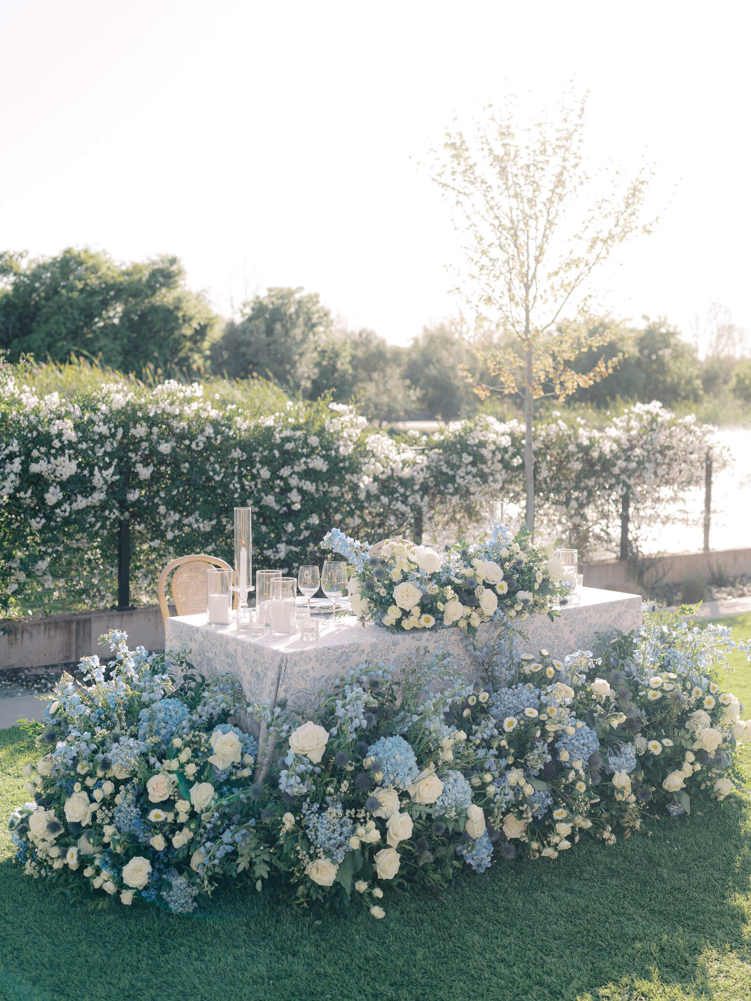 The sweetheart table at a destination wedding reception surrounded by blue and white flowers.