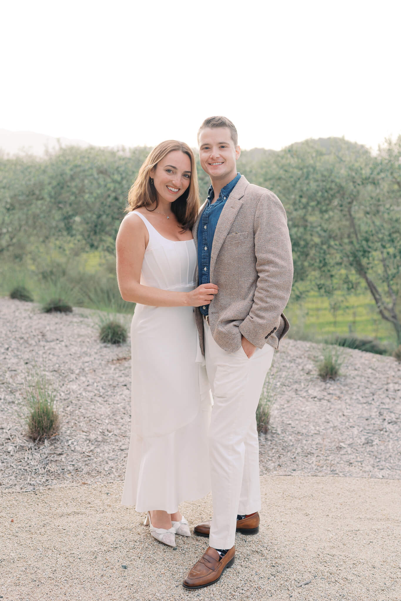 A bride and groom at standing arm in arm at their rehearsal dinner.