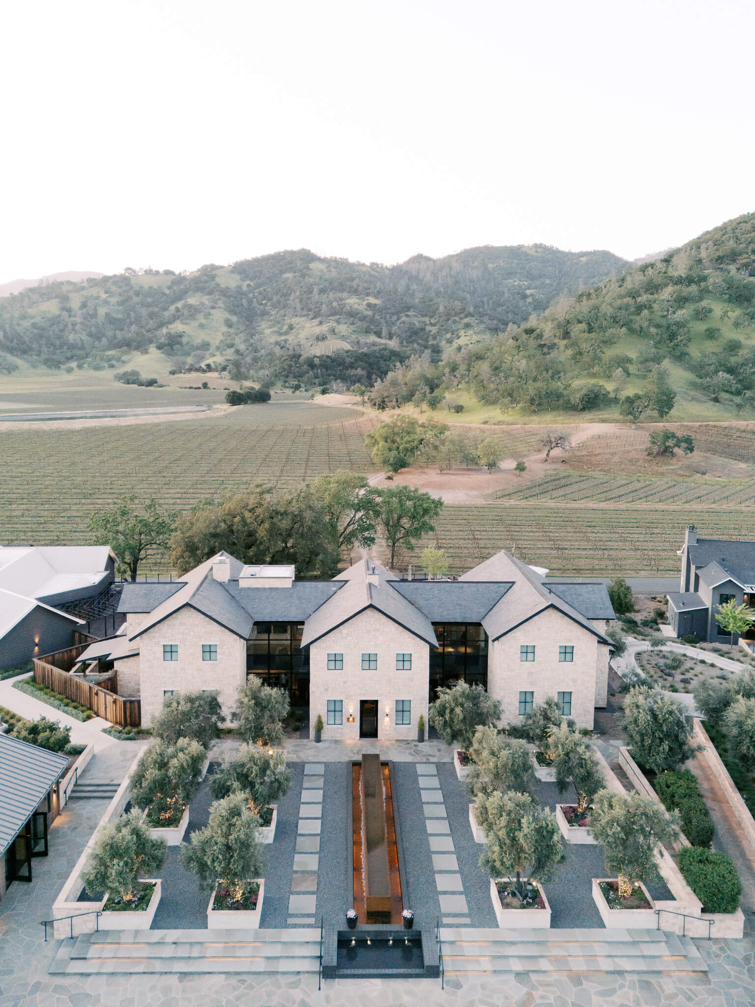 Drone shot of the destination wedding venue during sunset with mountains in the background.