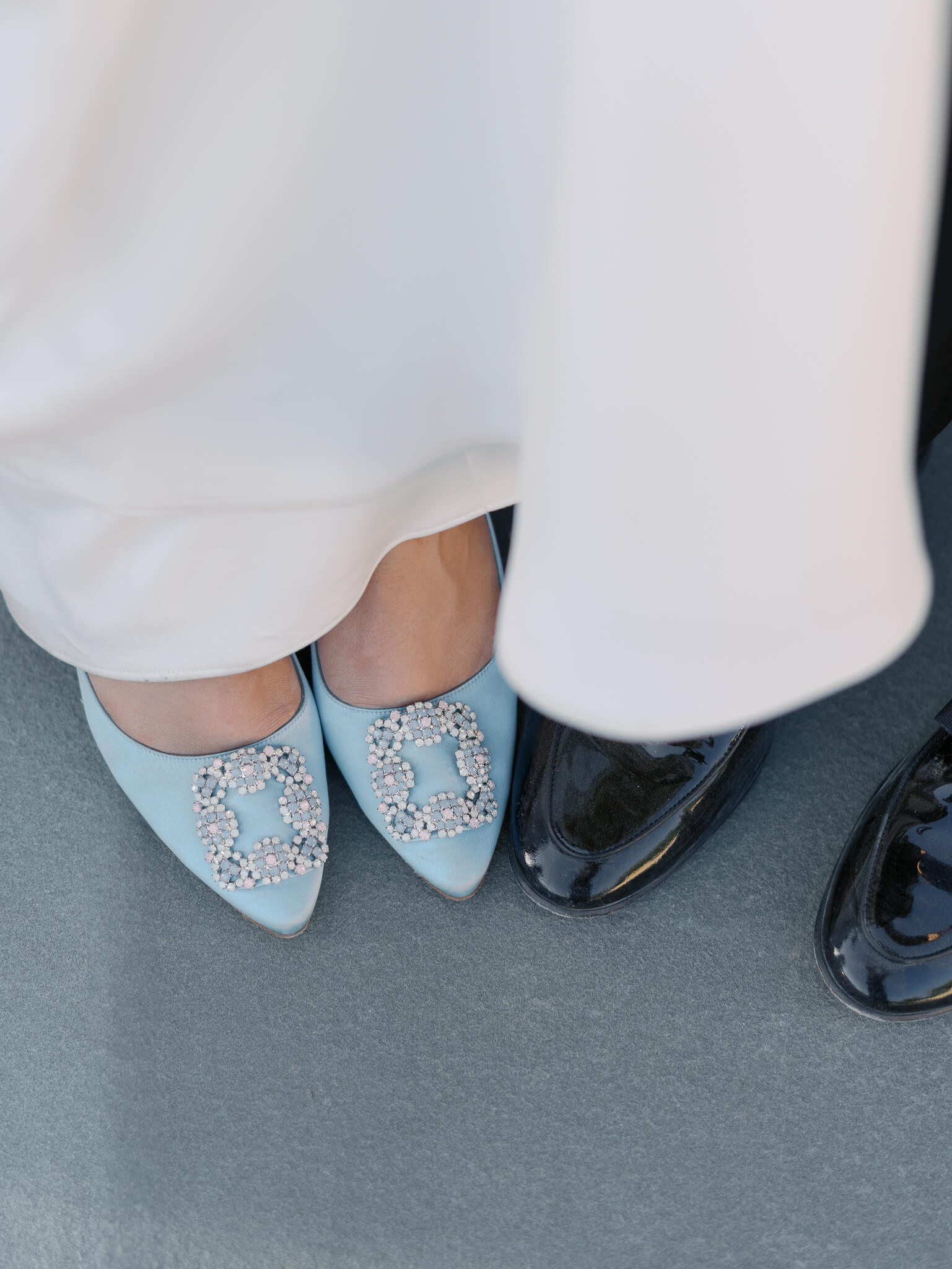 Closeup of a bride and grooms blue and black shoes.