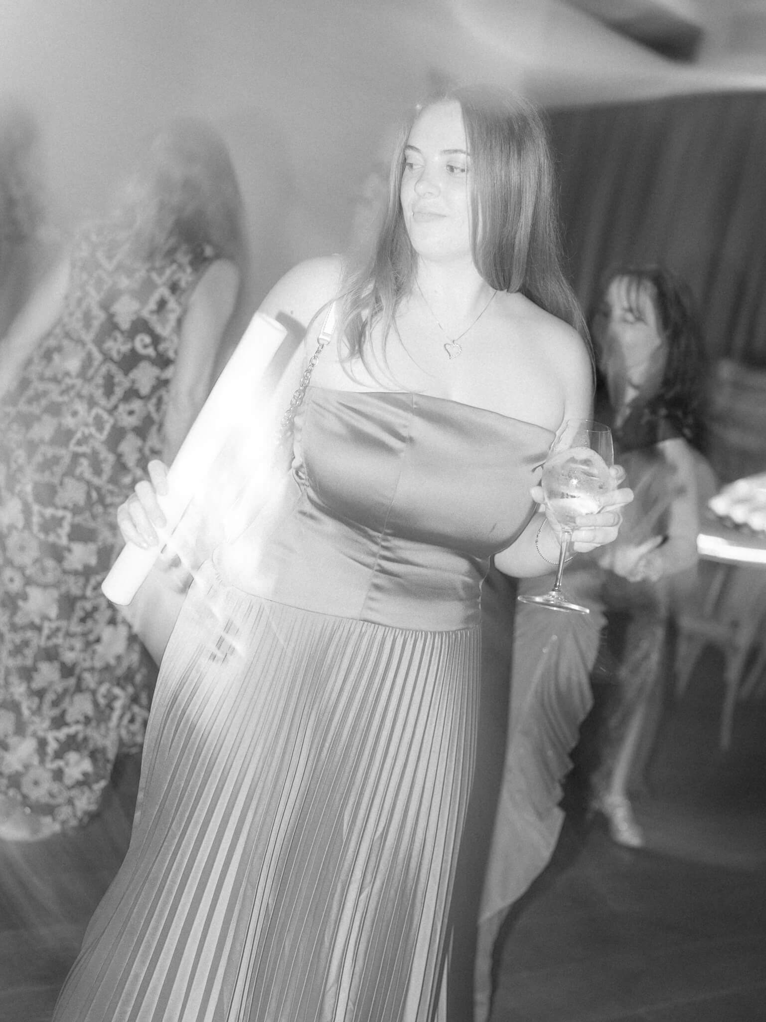 Black and white image of female wedding guests dancing at a destination wedding weekend.