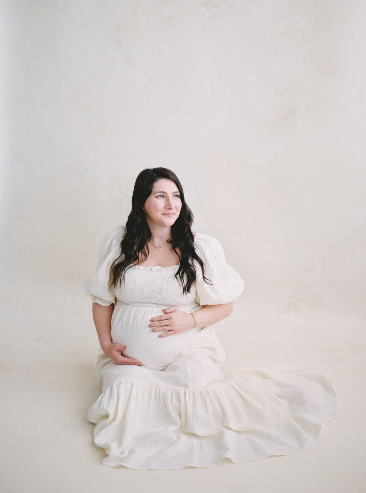 A pregnant mother sitting and holding her belly for her Annapolis maternity photos.